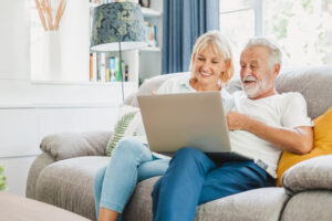 Couple senior using computer laptop on sofa at home for online s